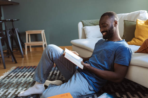 istock Man enjoys relaxing at home while reading a book in cozy atmosphere 2202458504