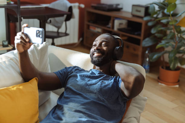 istock Young man watching videos on a smartphone at home 2202458682