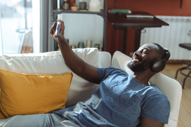 istock Young man watching videos on a smartphone at home 2202458690