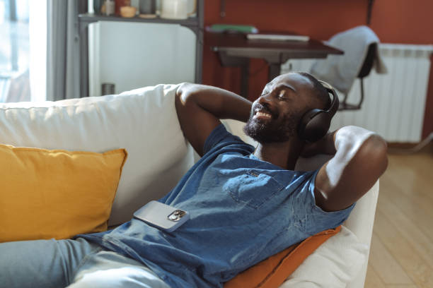 istock Man relaxing with music on headphones while lounging on a comfortable sofa 2202458738