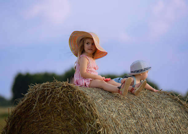 Mother hugging her little daughter back view, yellow ripe wheat field nature background, sunset golden hour