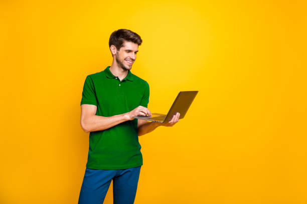 istock Portrait of his he nice attractive content cheerful cheery guy using laptop working online isolated over bright vivid shine vibrant yellow color background 2202459713