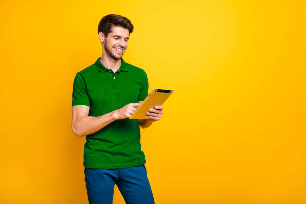 istock Portrait of his he nice attractive cheerful cheery content guy using digital ebook spending free time isolated over bright vivid shine vibrant yellow color background 2202459728