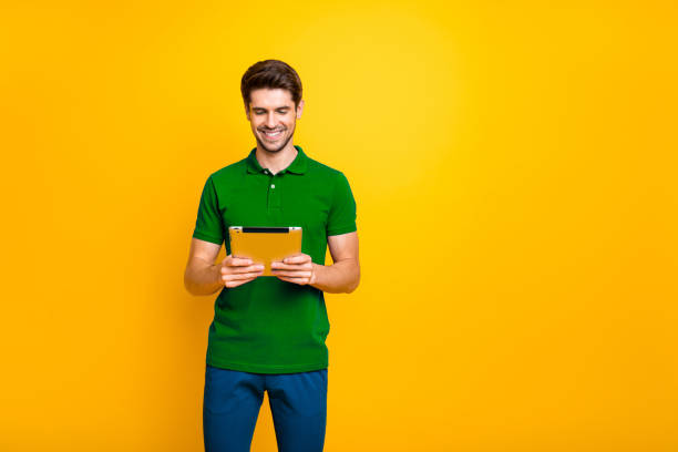 istock Portrait of his he nice attractive focused cheerful cheery guy using reading ebook isolated over bright vivid shine vibrant yellow color background 2202459733