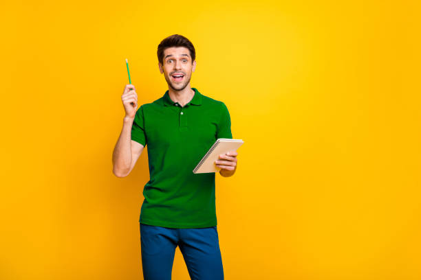 istock Portrait of his he nice attractive genius focused cheerful cheery glad guy creating making notes cool idea isolated over bright vivid shine vibrant yellow color background 2202459751