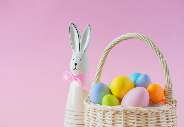 istock Basket with colorful Easter eggs and Bunny on a pink background, copy space 2202460117