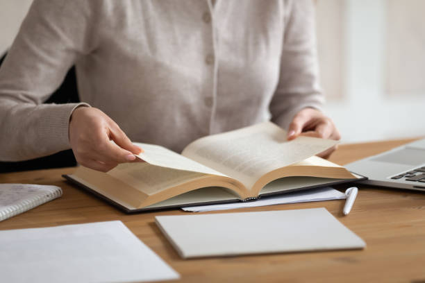 istock Female student busy studying reading book in classroom 2202464022
