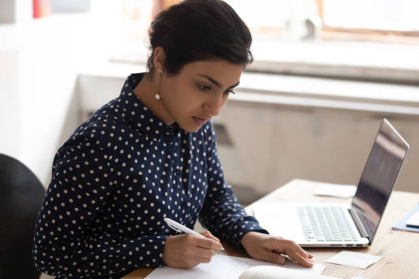 istock Focused indian girl buys writing studying using laptop 2202464072