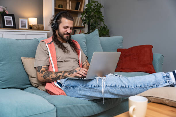 istock Business man in home environment, Laptop, wireless headphones and a smile for productive work from home. Working in style. Independent satisfied expert, freelance male stress-less job occupation. 2202465501