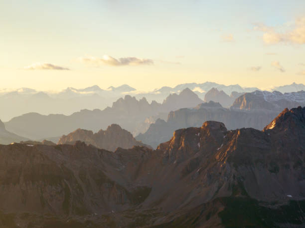 istock Dreamy mountain panorama, golden sunrays illuminating Dolomites, creating soft atmospheric glow. Silhouettes of peaks blend into mist, forming stunning alpine landscape. Nature aerial view 2202466836