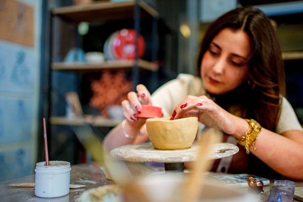 istock A young woman carefully paints a small clay cup during a pottery class 2202467720