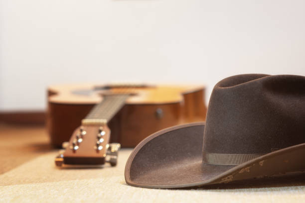 brown cowboy hat and acoustic guitar out of focus in background - country music and line dance - text space on top
