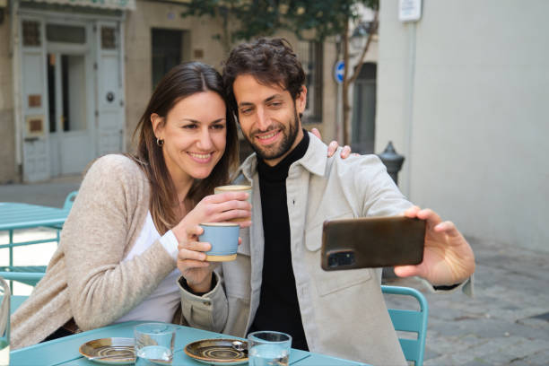 istock Happy couple taking a selfie while enjoying coffee at outdoor cafe 2202468255