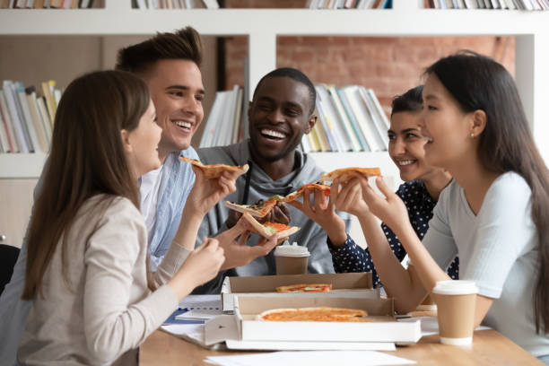 istock Happy multiethnic young people enjoy pizza in classroom 2202468941