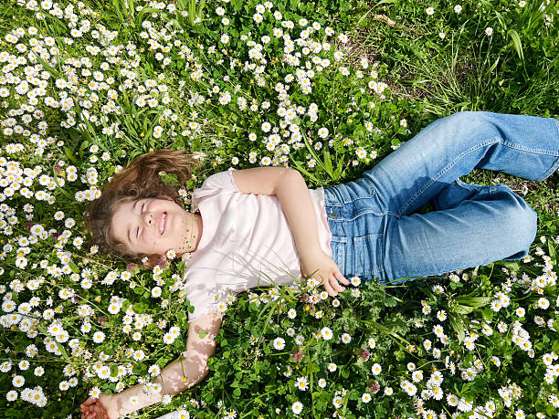 istock Girl lying on green grass with daisy flowers 2202468994