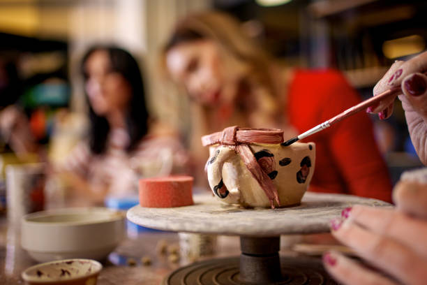 istock A young woman carefully paints a small clay cup during a pottery class 2202469081
