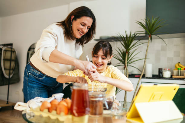 istock Mom and daughter baking chocolate cookies together in modern kitchen 2202469086