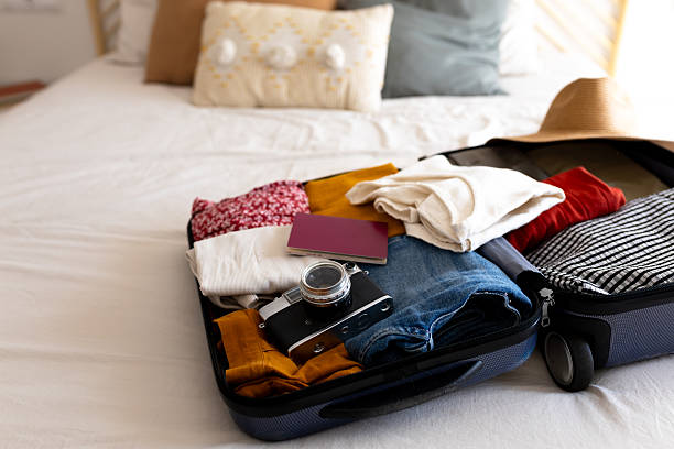 istock Suitcase packed with clothes, passport, and camera ready for vacation 2202469319