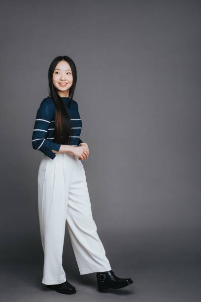 istock Cheerful Asian woman posing on a grey background 2202469609
