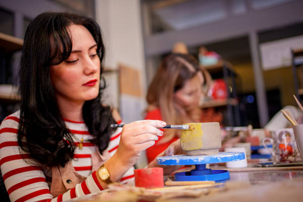 istock A young woman carefully paints a small clay cup during a pottery class 2202469685