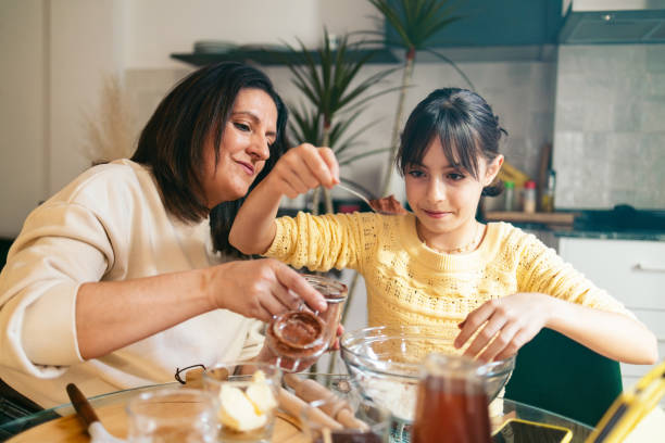 istock Mom and daughter adding chocolate to cookie dough in modern kitchen 2202471976