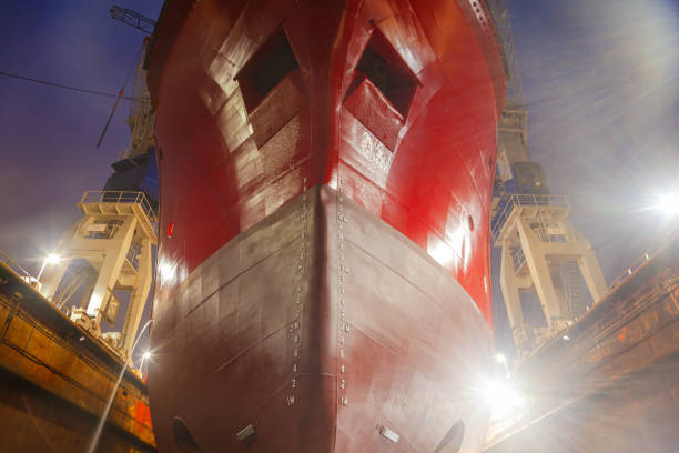 A ship standing in a dry dock at night under the light of lanterns.