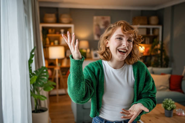 istock Young woman laughing and gesturing while standing in living room 2202472719