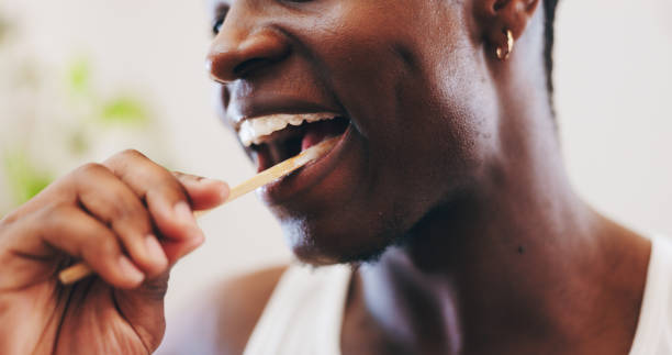 istock Black man, hands or brushing teeth with toothbrush for dental hygiene, morning routine or fresh breath at home. Closeup, male person or smile with bamboo stick for oral, mouth or gum care in bathroom 2202473034