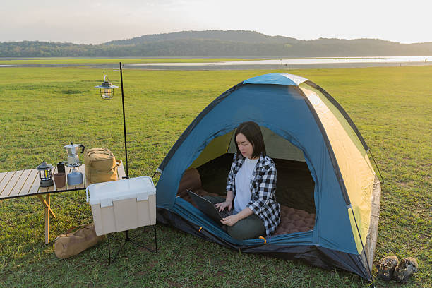 istock Freelance woman working on laptop while camping outdoors 2202474751