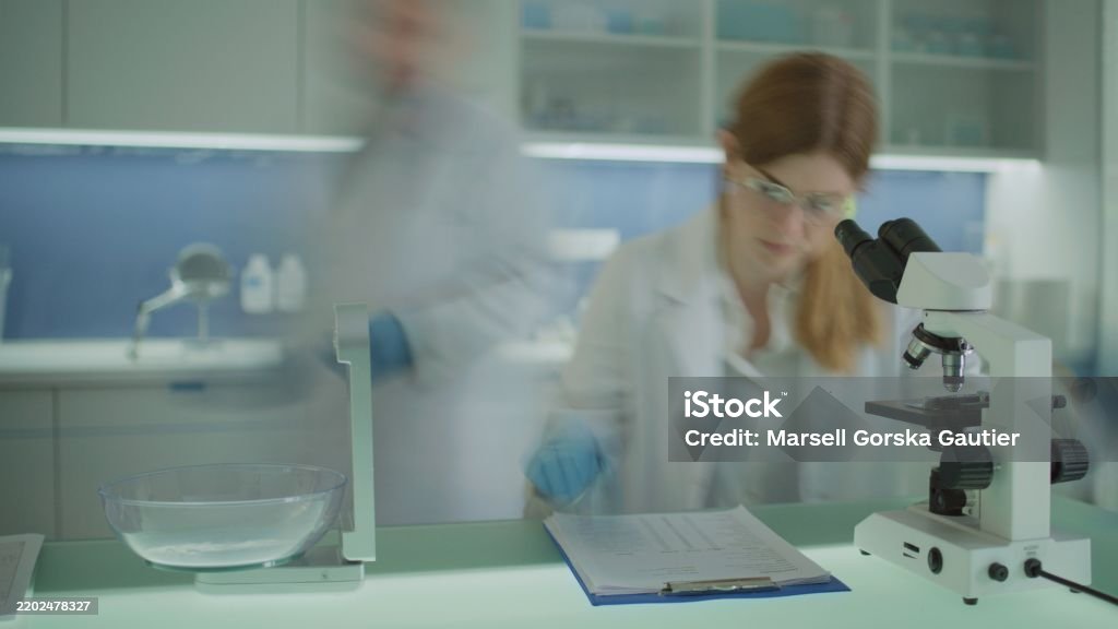 Lab Worker Front View A Laboratory Worker Looks Through A Microscope And Records The Tests In ...