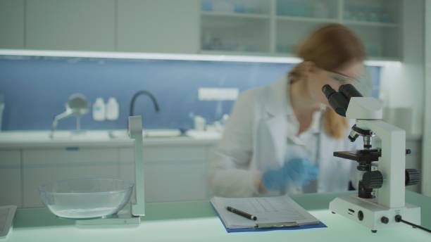 istock A laboratory worker looks through a microscope and records the tests in a questionnaire. 2202478338
