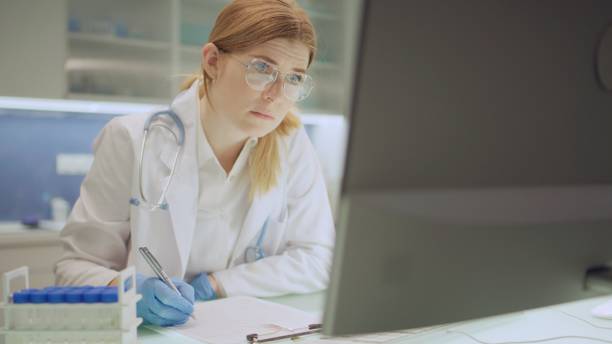 istock The laboratory employee compares the data from the survey with the document on the computer. 2202478521