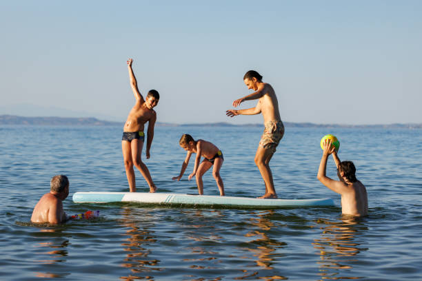 istock Kids and Dad Competing on a Surfboard 2202480262