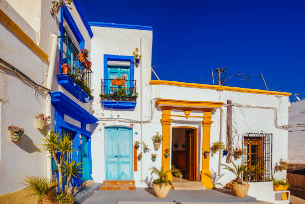 istock whitewashed facades with coloured windows and doors in a village street decorated with pots and plants. 2202481201