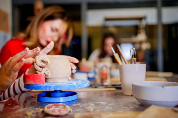 istock A young woman carefully paints a small clay cup during a pottery class 2202481408