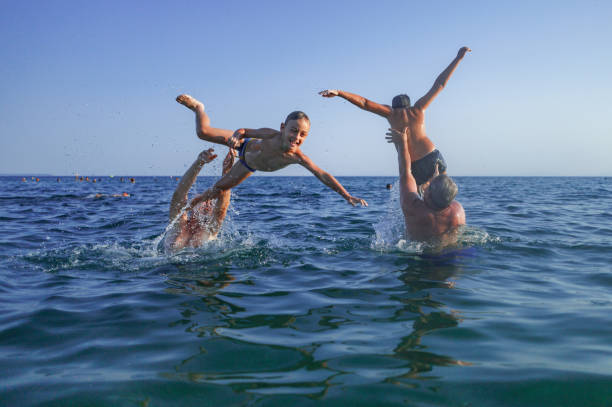 Happy teenager boys, running and playing on the beach on sunset, splashing water and jumping on the sand. Tel Aviv, Israel