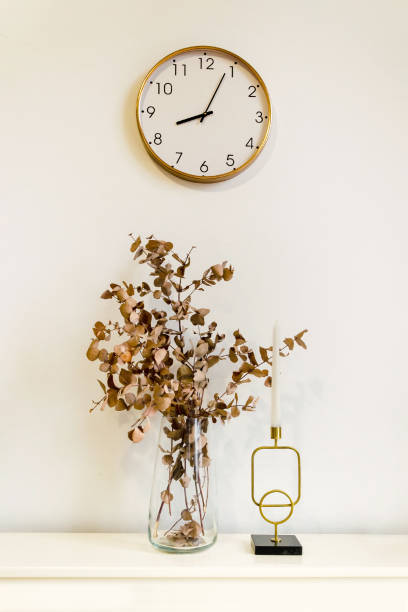 istock Minimalistic interior decor: branches of dried plants in vase, candle in candlestick, clock on wall 2202494092