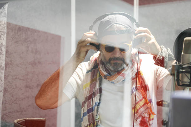 Young happy DJ playing music during a party on the beach and turning towards the camera.