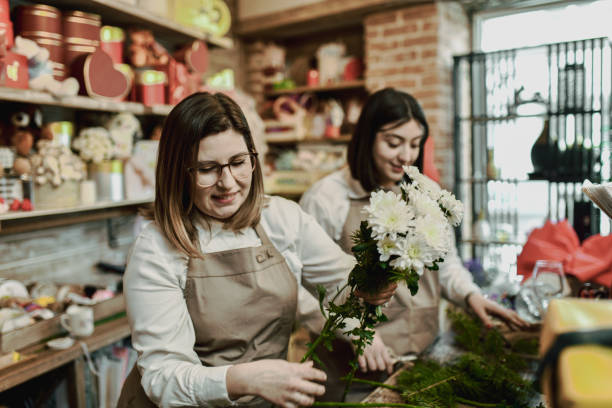 istock Beautiful Female Florists Looking Joyful While Creating Bouquets 2202506356