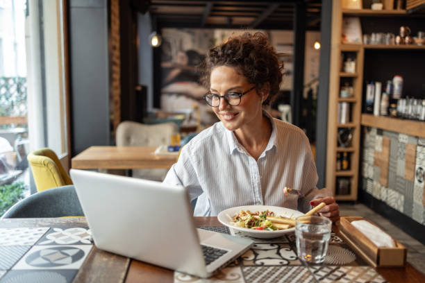 istock Freelancer woman working remotely and eating a salad in restaurant 2202506612