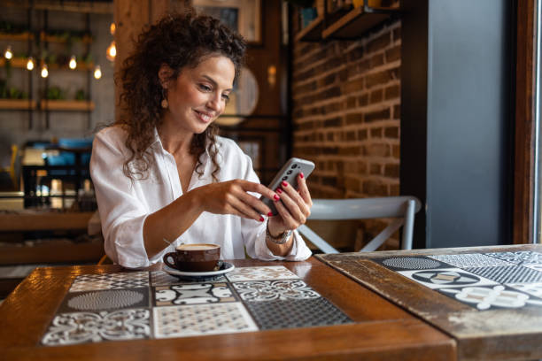 istock Elegant woman using mobile phone in cozy cafe 2202511624