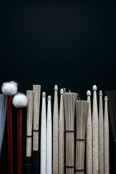 Various drumsticks, jazz brushes, brooms lying on a black background.