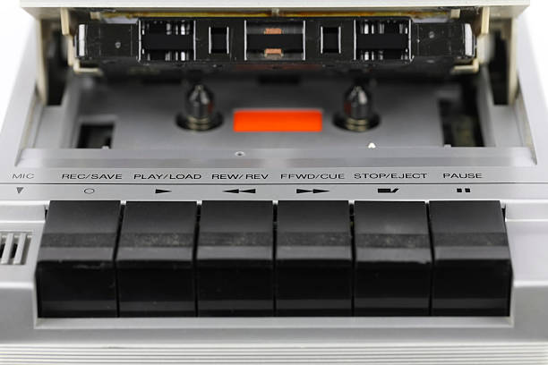 An old portable tape recorder. A compact cassette is inside the open cassette door. The panel of buttons for selecting record, play, fast forward, rewind, stop-eject functions is visible.