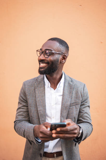Confident businessman smiling while using smartphone outdoors