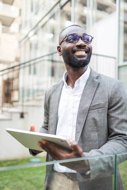 istock Confident businessman with tablet standing outside modern office building 2202516846