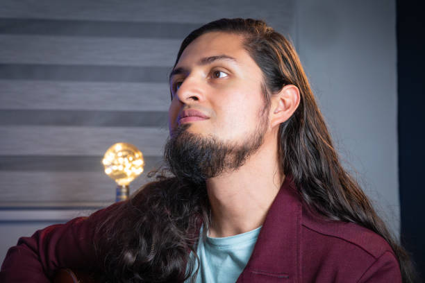Thoughtful man with long hair in cozy indoor setting. Hispamic man thoughtful