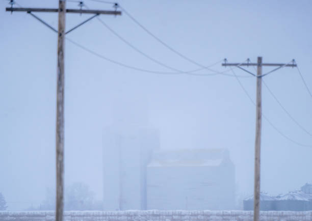 istock Grain elevator and power lines disappearing into the fog on a cold winter day 2202524395