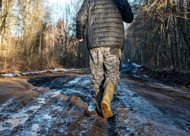 istock dirty, muddy road, human feet in rubber boots wade through the mud 2202524665