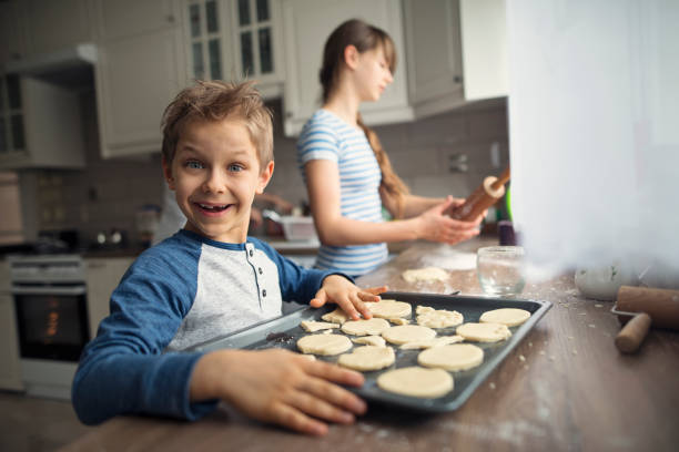 istock Funny little boy and his sister making dough in the kitchen 2202527580