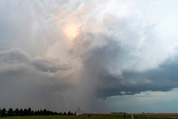 Ominous storm clouds are gathering over a small church in a rural landscape, creating a dramatic and powerful scene